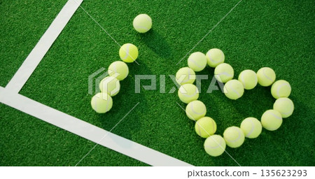 Displaying yellow tennis balls forming I heart shape on tennis court corner, with white court lines 135623293