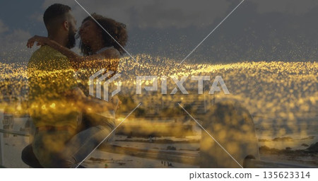 Kissing romantic couple on metal railing at sandy beach and ocean waves, golden light scattering Kissing romantic couple on metal railing at sandy beach and ocean waves, golden light scattering 135623314