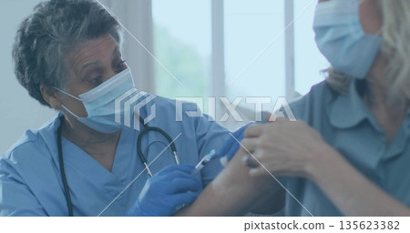 Injecting nurse administering vaccine to patient at clinic, with syringe, gloves, mask, copy space Injecting nurse administering vaccine to patient at clinic, with syringe, gloves, mask, copy space 135623382