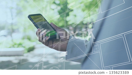 Showing male wearing suit jacket holding smartphone on park path, with green COVID pass QR code 135623389