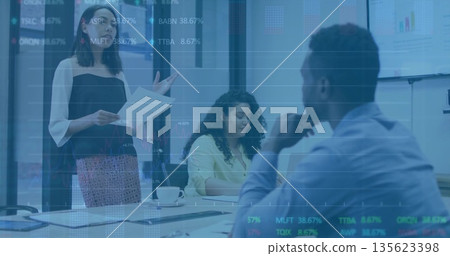 Standing woman in blouse presenting papers at meeting table, with laptop, coffee mug, copy space Standing woman in blouse presenting papers at meeting table, with laptop, coffee mug, copy space 135623398