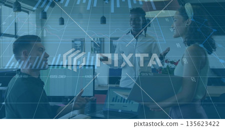 Discussing data among three colleagues in business attire in office, dual monitors and potted plant 135623422