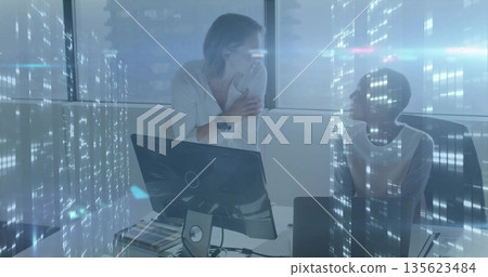 Discussing design two professional women leaning on desk using monitor at office, with swatch book Discussing design two professional women leaning on desk using monitor at office, with swatch book 135623484
