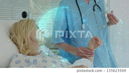 Healthcare worker in blue scrubs checking patient's pulse and preparing syringe in hospital room Healthcare worker in blue scrubs checking patient's pulse and preparing syringe in hospital room 135623509
