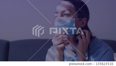 Adjusting worker wearing scrubs surgical mask in staff lounge with stethoscope on couch, copy space 135623510