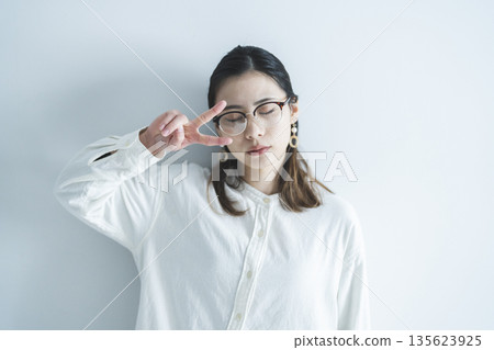A woman wearing glasses making a peace sign 135623925
