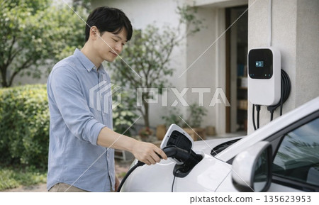 A man charging his electric car in front of his house - eco-friendly lifestyle 135623953