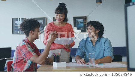 Presenting Asian woman holding printed charts and pen at meeting room, with colleagues listening Presenting Asian woman holding printed charts and pen at meeting room, with colleagues listening 135624549