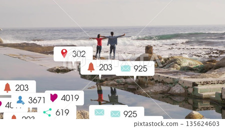 Stretching couple facing ocean on coastal platform, with notification icons floating Stretching couple facing ocean on coastal platform, with notification icons floating 135624603
