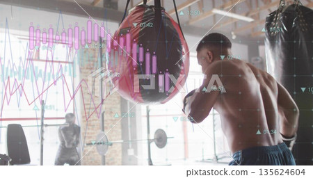 Punching shirtless male athlete delivering strike to red punching bag at gym, with data overlays 135624604