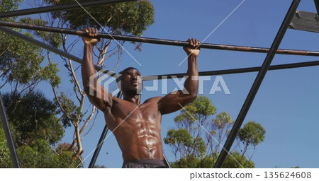 Pulling shirtless man showcasing defined abs and arms at outdoor gym, with metal pull-up bar Pulling shirtless man showcasing defined abs and arms at outdoor gym, with metal pull-up bar 135624608