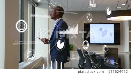 Gazing professional in suit holding smartphone in conference room by monitor, with data overlays 135624632