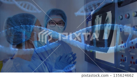 Doctors wearing surgical masks and gowns reviewing X-ray scans and DNA helix at lab control panel 135624662