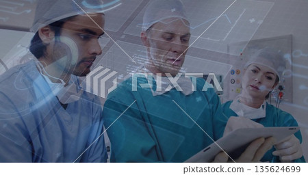 Gathering three surgeons examining tablet projecting holographic data in hospital OR, monitors Gathering three surgeons examining tablet projecting holographic data in hospital OR, monitors 135624699