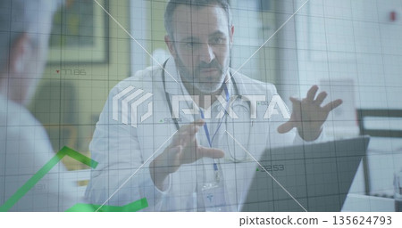 Pointing doctor wearing white coat and stethoscope explaining laptop data in exam room, ID badge 135624793