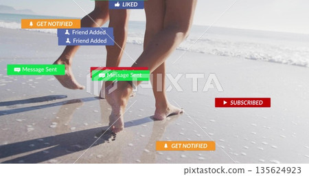 Walking barefoot couple gliding along wet sandy shoreline, showing floating social notifications Walking barefoot couple gliding along wet sandy shoreline, showing floating social notifications 135624923