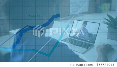 Man watching colleague gesturing on laptop at white desk, potted plant, translucent graph overlay Man watching colleague gesturing on laptop at white desk, potted plant, translucent graph overlay 135624943