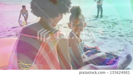 Spending time Black family kneeling and playing on sandy beach near water, with colorful beach ball 135624981