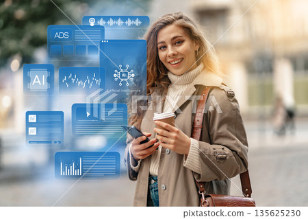Woman smiles while holding a cup and smartphone in a city street during daytime Woman smiles while holding a cup and smartphone in a city street during daytime 135625230