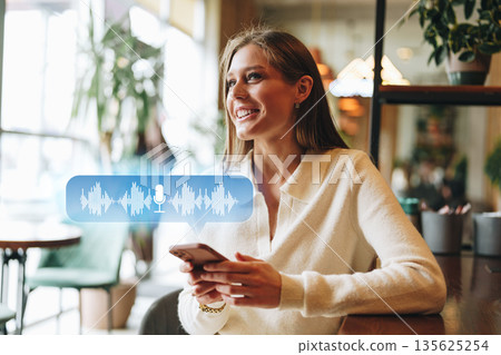 Woman enjoying time in cafe while using smartphone for voice messaging Woman enjoying time in cafe while using smartphone for voice messaging 135625254