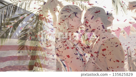 Embracing couple wearing vacation attire on ocean shore, with bunting flags, confetti, palm fronds Embracing couple wearing vacation attire on ocean shore, with bunting flags, confetti, palm fronds 135625829