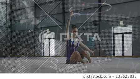 Teenage rhythmic gymnast wearing blue leotard balancing hoop overhead on mat in gym, hoop artistry Teenage rhythmic gymnast wearing blue leotard balancing hoop overhead on mat in gym, hoop artistry 135625835