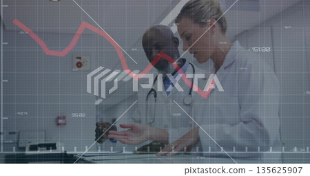 Reviewing data doctors using touchscreen table in hospital corridor, stethoscope and red line graph 135625907