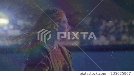 Woman wearing heavy coat knit sweater on railing at dusk, flare and city lights, copy space Woman wearing heavy coat knit sweater on railing at dusk, flare and city lights, copy space 135625967