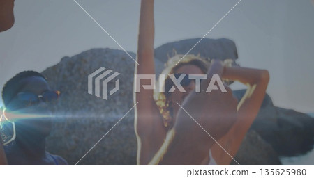 Four friends in swimwear and sunglasses taking selfie on rocky shore, with smartphone lens flare Four friends in swimwear and sunglasses taking selfie on rocky shore, with smartphone lens flare 135625980