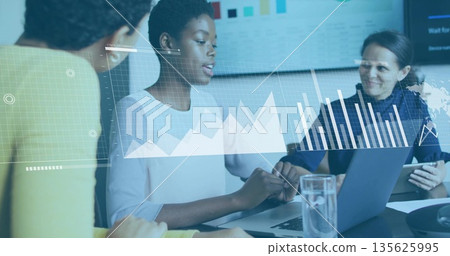 Analyzing data on laptop in conference room with tablet, displaying bar charts on display screen 135625995