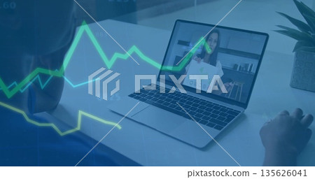 Hosting remote team reviewing checklist on laptop at home desk with line graphs and desk plant 135626041