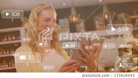 Woman holding tablet tapping screen in retail shop, with shelving and digital overlays, copy space 135626043
