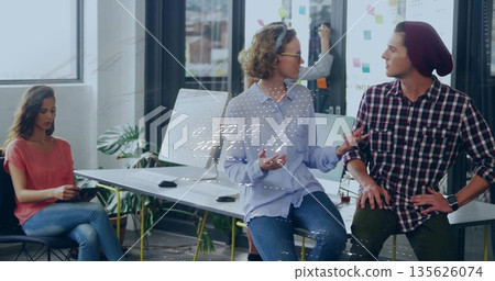 Two colleagues in knit cap and shirt discussing project ideas in office, with sticky note wall Two colleagues in knit cap and shirt discussing project ideas in office, with sticky note wall 135626074