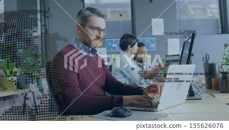 Typing mature man wearing glasses and sweater at desk in modern office, with laptop and mouse 135626076