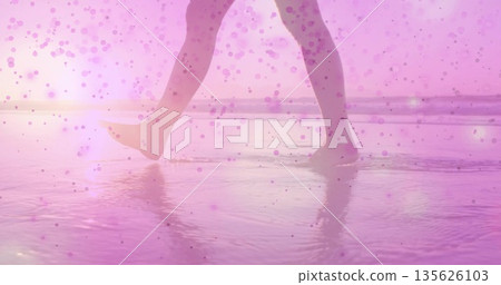 Walking woman's legs and feet through shallow water at beach golden hour, pink bokeh overlay Walking woman's legs and feet through shallow water at beach golden hour, pink bokeh overlay 135626103