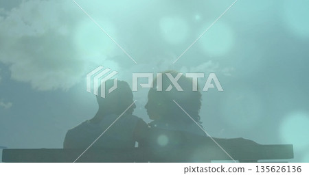 Leaning couple sharing moment on overlook wooden bench showing backlit silhouettes and lens flares 135626136