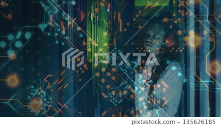 Woman examining server rack in data center, with circuit overlay and indicator lights, copy space 135626185