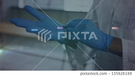 Applying blue nitrile gloves doctor wearing white lab coat in clinical lab, with blurred cabinets 135626189