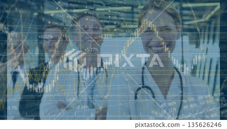 Posing doctors wearing lab coats and stethoscopes in hospital corridor, with market charts overlay 135626246