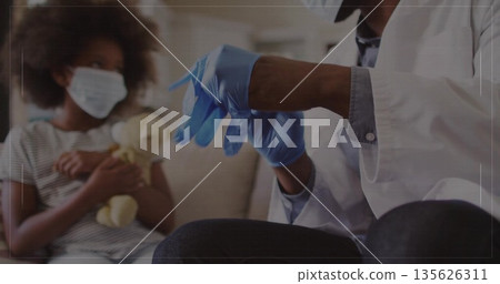 Doctor in white coat donning gloves in clinic, with masked child on gray couch holding doll Doctor in white coat donning gloves in clinic, with masked child on gray couch holding doll 135626311
