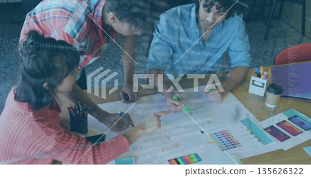 Collaborating professionals pointing, marking, leaning over office table, with mockups, markers 135626322