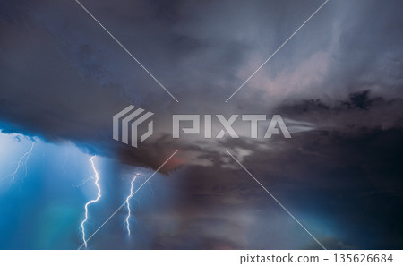 Dramatic lightning strike during severe thunderstorm with dark clouds over horizon 135626684