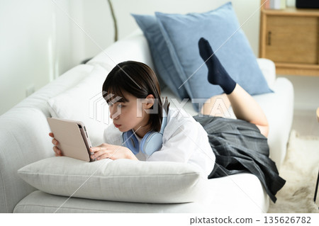 A woman watching a tablet on a sofa A woman watching a tablet on a sofa 135626782