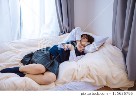 一個穿著校服的高中女生在床上哭泣 135626796