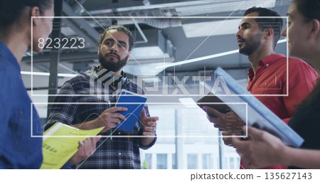 Discussing data man wearing plaid shirt and headphones holding notebook in office with UI overlay 135627143