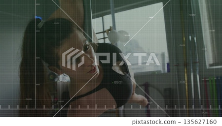 Balancing on polished pole, pole dancer wearing top and leggings practicing in studio, with mirror 135627160