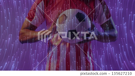 Holding classic soccer ball, athlete in red white striped jersey against purple studio backdrop Holding classic soccer ball, athlete in red white striped jersey against purple studio backdrop 135627210
