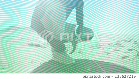 Crouching mid-adult man dipping hand into clear turquoise water at rocky shoreline, with flat rock Crouching mid-adult man dipping hand into clear turquoise water at rocky shoreline, with flat rock 135627219