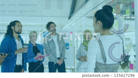 Presenting woman wearing plaid dress writing on glass board with sticky notes in office, copy space Presenting woman wearing plaid dress writing on glass board with sticky notes in office, copy space 135627296