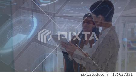 Standing two designers holding tablet with measuring tape, studying holographic interface in studio 135627351